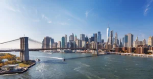 Iconic view of Brooklyn Bridge with Manhattan skyscrapers in the background, captured from Dumbo, showcasing urban elegance under a radiant sky