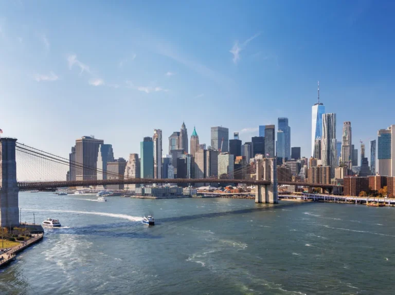 Iconic view of Brooklyn Bridge with Manhattan skyscrapers in the background, captured from Dumbo, showcasing urban elegance under a radiant sky